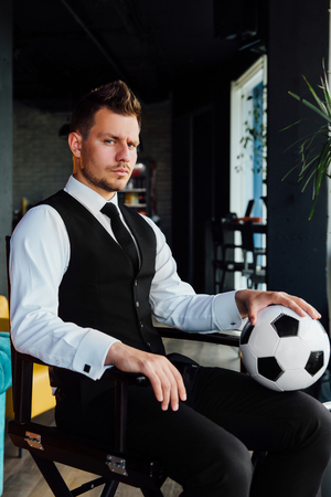 Stylish athletic man in a business suit and a soccer ball. Against the background of a loft wall.の写真素材