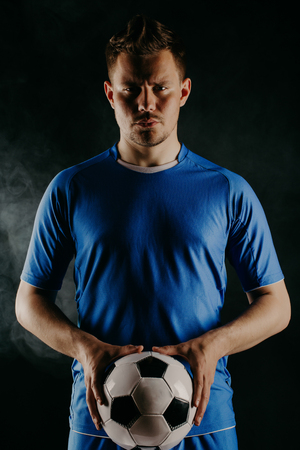 Young soccer player with ball on black background in studio.の写真素材