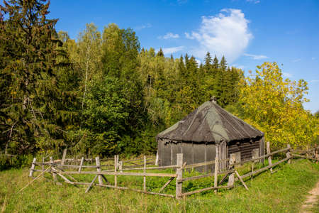 An old village house with a broken fence in a picturesque wildernessの写真素材