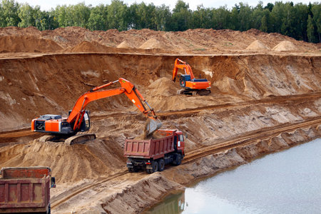 Loading sand into trucks on the sandy career, Mining. Excavators and trucks
