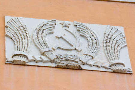 Obninsk, Russia - August 2019: A typical old Soviet stucco molding on a building with the image of spikes, a sickle and a hammer and the inscription "USSR"のeditorial素材