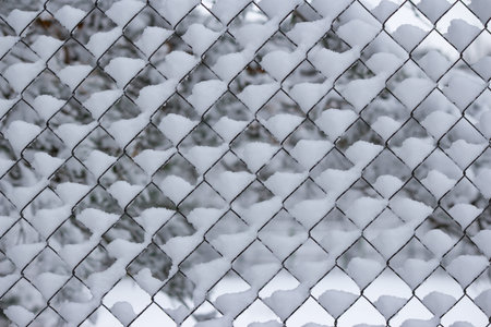 Mesh fence covered with white snow in winter