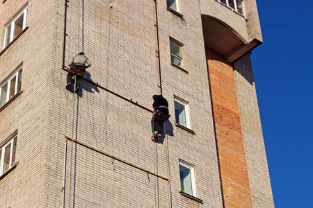 Industrial climbing. Workers hang the advertising on a building. Work at heightの写真素材