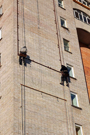 Industrial climbing. Workers hang the advertising on a building. Work at heightの写真素材