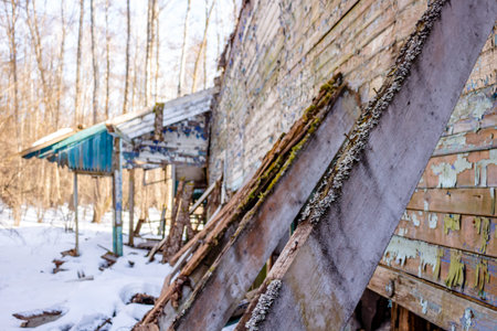 Demolished wooden structure in a forest area in winter. Former pioneer camp in Russia
