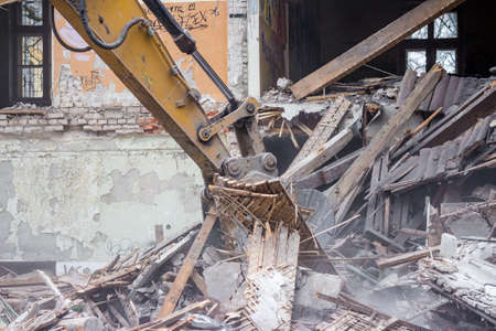 Demolition of an old brick building with an excavator bucketの写真素材
