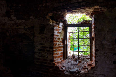 Broken window with wrought iron grating in the old abandoned buildingの写真素材