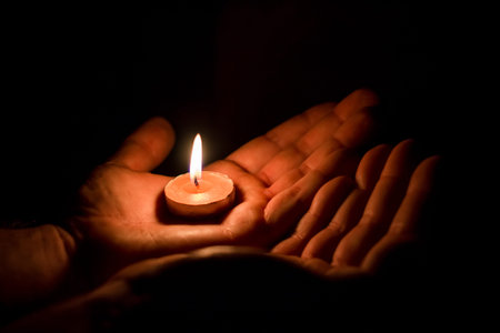 Burning candle on the palm, sorrow and memory