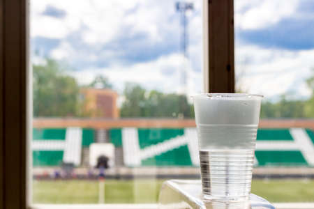 A plastic glass with water in the gym. View of the stadiumの写真素材