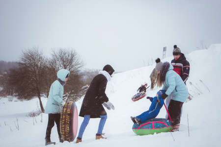 Borovsk, Russia - March 2018: Residents of the city of Borovsk ride on an ice hill on pillows, a cloudy winter dayのeditorial素材