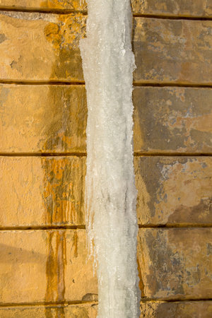 Icy pipe for rainwater on the facade of the house in winterの写真素材
