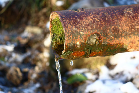 Metal pipe with flowing spring waterの写真素材