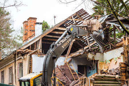 Demolition of an old wooden log house with a Volvo excavator: Kaluzhskiy region, Russia - April 2021