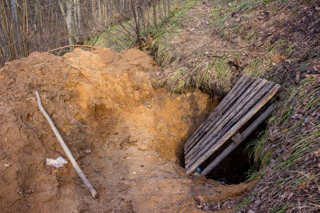 A dugout dug in the sand covered with a wooden pallet, digging tunnels in the sand on the slope of a...