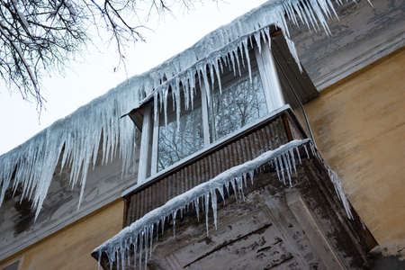 Large sharp icicles cover the roof and balcony at an apartment buildingの写真素材