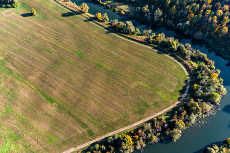 A sharp bend in a river that flows between forest and agricultural fields, aerial viewの写真素材