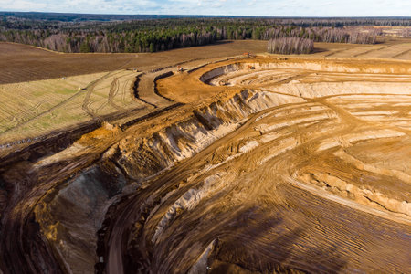 Aerial view of a growing sand pit at the expense of fields, overburden removal by excavators before...