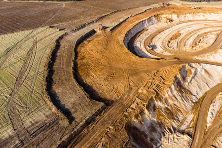 Aerial view of a growing sand pit at the expense of fields, overburden removal by excavators before sand extractionの写真素材