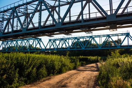 Metal structures of railway bridges and a country road passing under them in the countrysideの写真素材