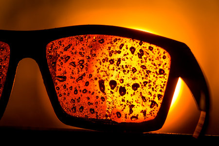 Sunglasses in water drops against the bright sunの写真素材