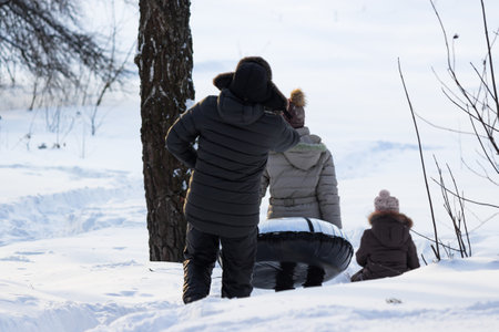 Family skiing in the winter from a slide on inflatable snow tubeの写真素材