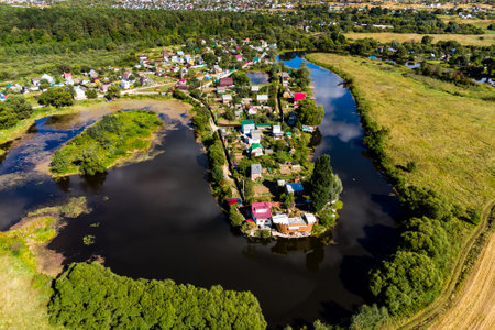 An aerial view of a dense suburban development on the shore of a winding reservoir. Ogublyanka lake in Kaluzhskiy region, Russiaの写真素材