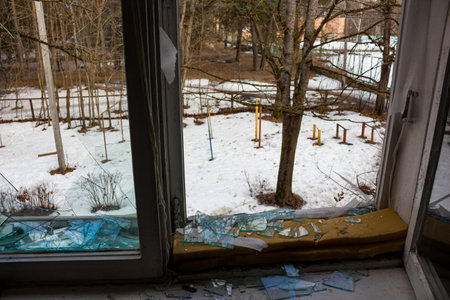 Broken window in an abandoned house overlooking the winter yard