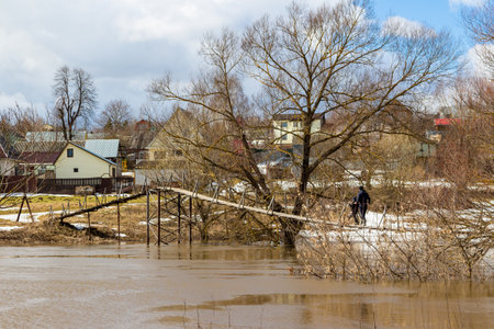 Suspension pedestrian bridge in the countryside during spring floodの写真素材