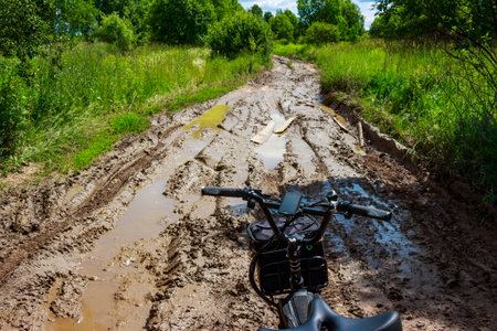 E-bike poised on a gnarly, muddy trail stretching into a lush green forest. Ready for a rugged off-road adventure through natureの写真素材