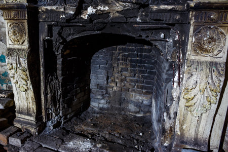 Blackened fireplace with damaged moldings in an old manorの写真素材