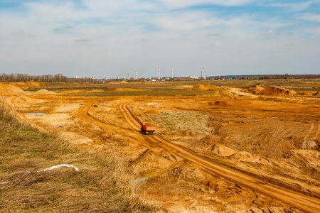 View from a hill on a sand quarry where a dump truck loaded with sand is drivingの写真素材