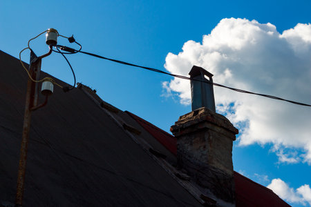 Roof of a village house with a chimney and a bracket for an electric wireの写真素材