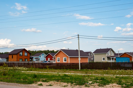 A vibrant row of newly built homes in a modern residential settlement under a clear August sky. This typical suburban development offers contemporary livingの写真素材