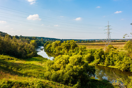 Power lines hanging over a river in the countrysideの写真素材