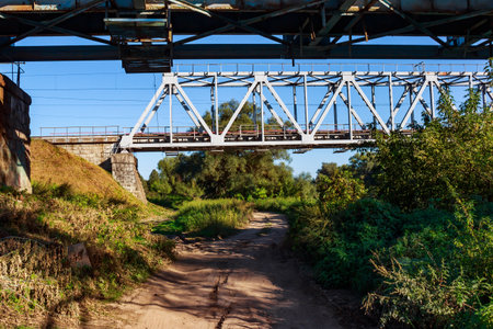 Country road passing under iron railway bridgesの写真素材