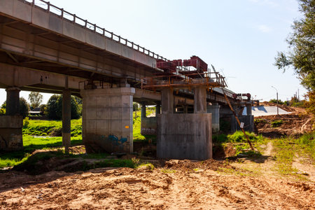 Concrete bridge expansion project underway, with new supports and steel frames. Construction site in summer, showing progress and infrastructure developmentの写真素材