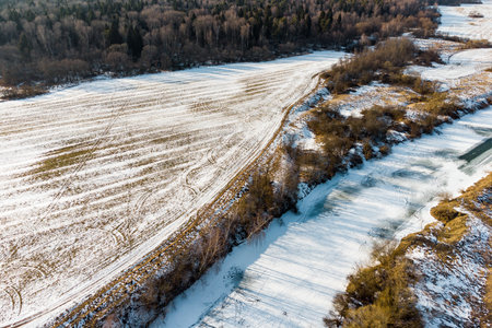 Aerial view of agricultural fields by the river during the winter seasonの写真素材