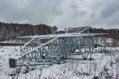 Metal construction of a transmission line support lying on a snowy field before installationの写真素材