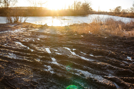 Mess of mud by the river against the backdrop of sunset, spring thaw in nature