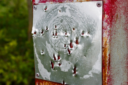 Old Soviet coat of arms on a metal plate, damaged by strong blows, Russiaの写真素材