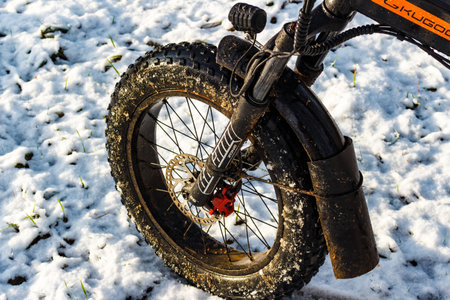 Close-up of a dirty fat tire electric bike wheel with disc brake and suspension fork stopped on...