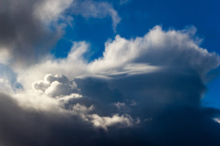 Dramatic cumulonimbus cloudscape against a deep blue sky. Intense storm formation with contrasting...