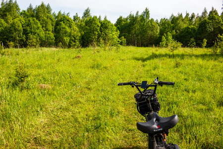 Electric bicycle parked in a vibrant green meadow, ready for an adventure through a lush forest, capturing the essence of a bright summer day: Russia - May 29, 2025のeditorial素材