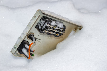 Roughly disassembled electrical enclosure, its guts exposed and buried in a pristine blanket of snow. Winter scene of forgotten electronic waste outdoorsの写真素材