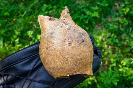 Broken ancient clay pot fragment held over a blurred background. Historical pottery artifactの写真素材