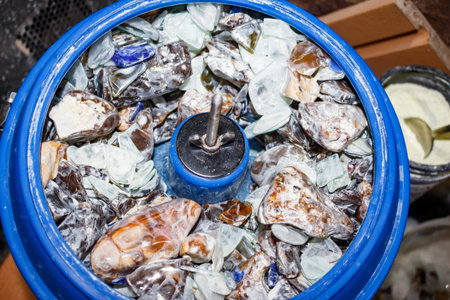 Stones rotating inside the bowl of a vibratory tumbling machine with white polishing powder Cerium...
