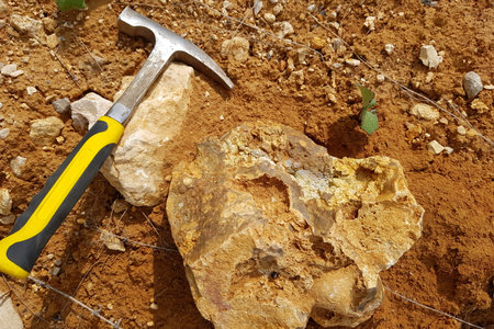 A geologist's hammer lies on the ground next to stones, a field photo from a geological expeditionの写真素材