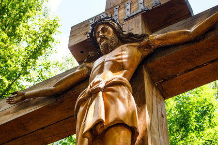 Bottom-up view of a wooden statue of Jesus Christ crucified on the cross with a crown of thorns on his head: Kutepovo, Kaluga Region, Russia - July 5, 2025のeditorial素材