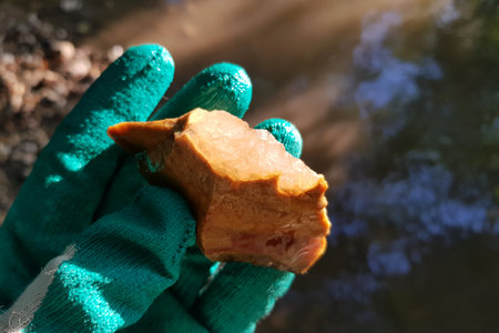 Crystalline quartz on a flint fragment in the sun, inspection of a mineral found near a river, field...