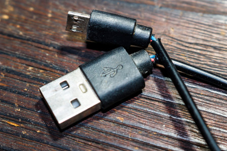 Frayed black USB and micro USB charging cable, insulation torn to reveal colorful internal wires. Symbolizes electronic device failure and wearの写真素材